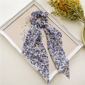 Détail du chouchou floral bleu en mousseline avec longs rubans sur un cadre vintage