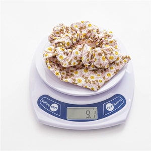 Floral print scrunchie weight test showing 9.1g on a digital scale for light comfort