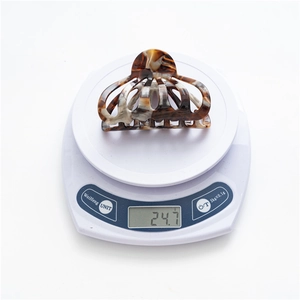 Detail shot of a large leopard acetate hair claw clip weighing 24.7g on a scale