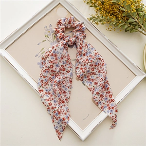 Chouchou à motif floral avec rubans présenté sur un cadre vintage avec des fleurs séchées