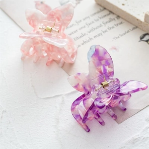 Gros plan de pinces à cheveux papillon avec texture marbrée rose et violette et ressorts