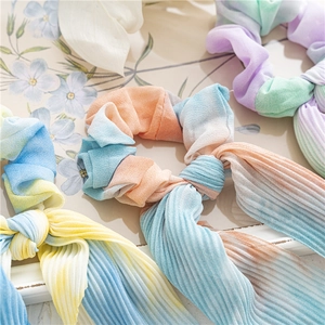 Détail d'un chouchou tie-dye plissé avec de longs rubans aux tons pastel dégradés