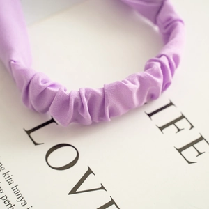 Close-up of lavender fabric headband showing soft pleated texture and elastic back band