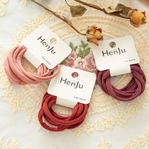 Detail of macaron elastic hair bands on branded cards over vintage lace tablecloth