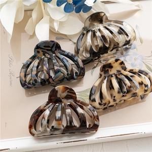 Detailed macro view of four large acetate hair claws in assorted marble and tortoise patterns