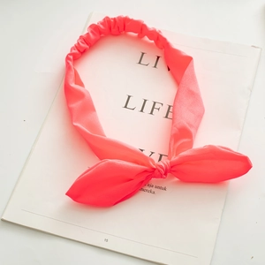 Detail of neon pink fabric headband with bunny ear knot and elastic pleated texture