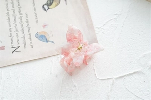 Détail macro d'une pince à cheveux papillon avec texture acétate marbré rose et blanc