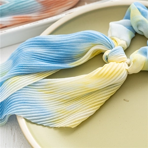 Gros plan sur chouchou plissé tie-dye avec rubans aux teintes bleu et jaune