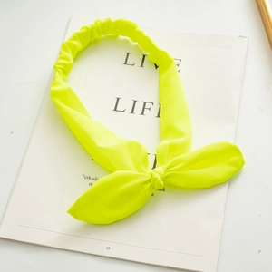 Detailed view of neon green fabric rabbit ear headband with elastic knotted soft texture