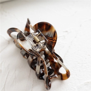 Detail of tortoiseshell acetate hair claw with hollow design and golden metal spring