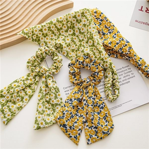 Flat lay of floral daisy hair scrunchies and matching triangle headscarves on a wooden tray
