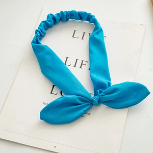 Detail of bright blue elastic bunny ear headband on a magazine with bow-knot fabric texture