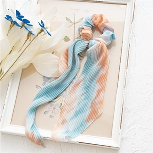 Détail de la texture plissée tie-dye et du ruban long sur le chouchou avec foulard