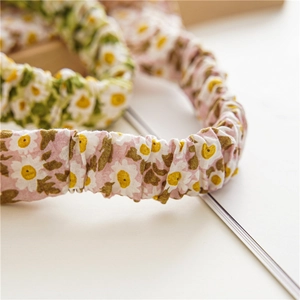 Detail of floral scrunchie hair ties with daisy pattern and elastic pleated fabric texture