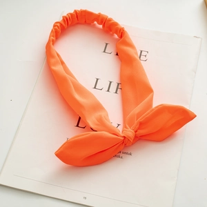 Detail showing the textured neon orange fabric and rabbit ear knot of the elastic headband