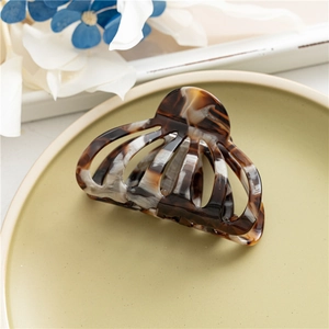 Close-up of tortoise shell pattern acetate hair claw clip on a light green tray