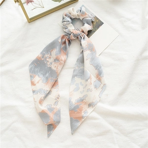 Gros plan d'un chouchou en satin tie-dye avec de longs rubans sur lin blanc pur