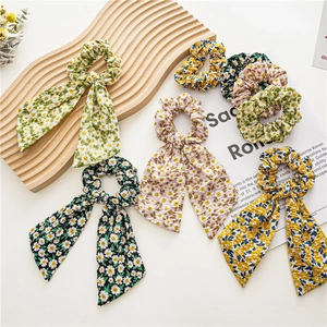 Multiple floral scrunchies with long ribbons on wooden background with vintage paper