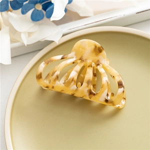 Detail of a large amber tortoiseshell hair claw clip displayed on a green ceramic plate
