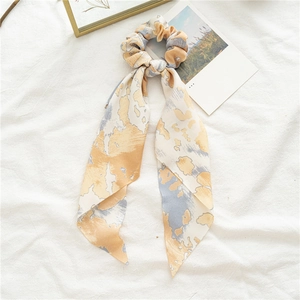 Vue détaillée du chouchou tie-dye gingembre avec rubans longs sur lin blanc doux