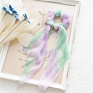 Détail d'un chouchou tie-dye plissé avec de longs rubans en mousseline violette et verte