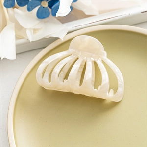 Detail view of large cream acetic acid hair claw clip with elegant marble pattern