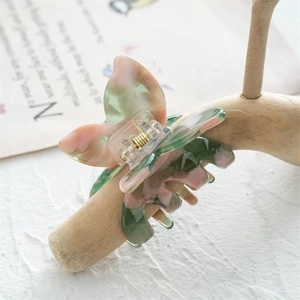 Détail de la pince à cheveux papillon en acétate marbré vert et rose sur support bois
