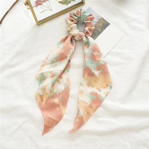 Chouchou en satin tie-dye avec rubans rose et vert sur un fond décoratif blanc élégant