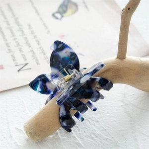 Macro d'une pince à cheveux papillon en acétate avec motif marbré bleu sur bois