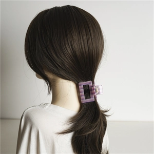 Pinza per capelli rettangolare in acrilico a righe viola indossata su capelli castani