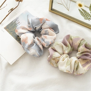 Détail de deux chouchous en satin surdimensionnés avec des motifs de tie-dye abstraits