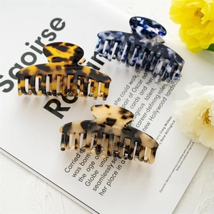 Three acetate hair claws in leopard, marble, and tortoiseshell patterns on magazine page