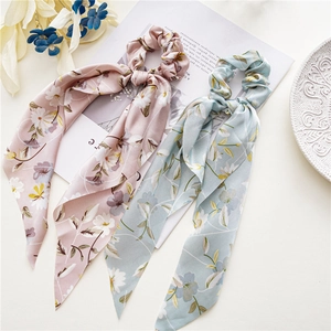 Draufsicht auf rosa und blaue Satin-Haargummis mit Blumenmuster und langen Bändern