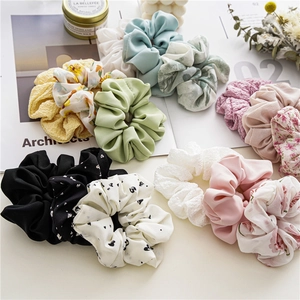 Σετ τριών λουλουδάτων scrunchies από σιφόν σε διάφορα παστέλ χρώματα σε λευκό γραφείο