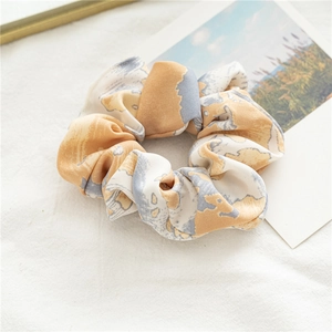 Détail d'un chouchou en satin tie-dye jaune avec texture de tissu doux et motif artistique