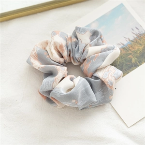 Détail d'un chouchou en satin avec texture marbrée tie-dye aux tons gris et orange
