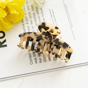 Detail of tortoise shell acetate hair claw clip showing glossy leopard pattern texture