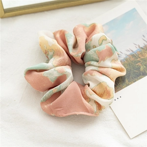 Détail d'un chouchou en satin tie-dye avec motifs aquarelle pastel sur tissu en lin
