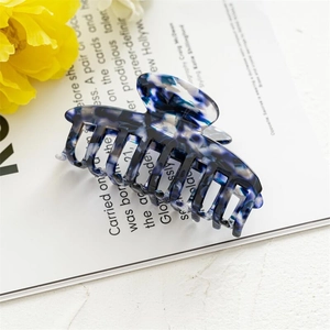 Detail view of blue and white marble acetate hair claw clip on fashion magazine background