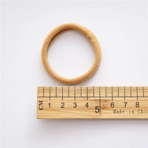 Elastic seamless hair tie in camel brown shown with ruler for size reference