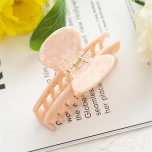 Detail showing the peach marbled acetate texture and metal spring of the large hair claw clip