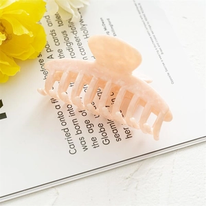 Detail of a large peach acetate hair claw clip on a stylish aesthetic background
