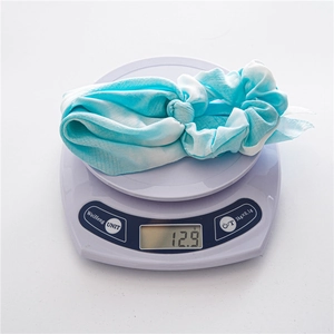 Gros plan d'un chouchou tie-dye sur une balance montrant un poids de 12,9 grammes