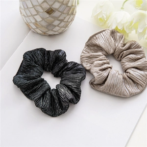 Détail de chouchous plissés noir et champagne avec une texture au lustre métallique