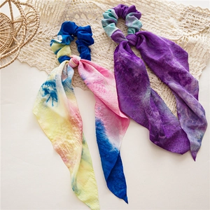 Chouchous en tissu tie-dye avec rubans longs sur un décor élégant en dentelle beige