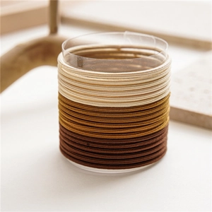 Close-up of earth tone seamless hair ties stacked on a cylindrical display stand