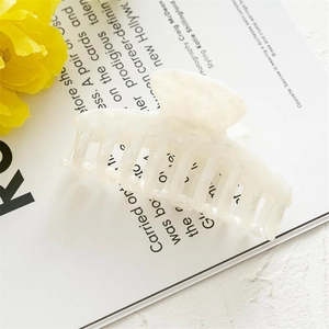 Detail of a large cream acetate hair claw clip with marble texture on an open magazine