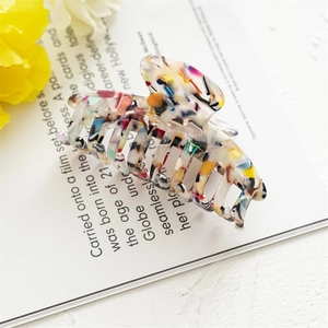 Detail of a 10cm acetate hair claw with colorful marble pattern on a magazine page