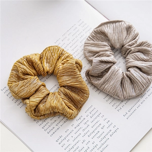 Détail des chouchous plissés dorés et champagne avec une texture métallique fine