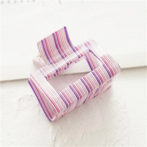 Dettaglio ravvicinato di una pinza per capelli quadrata in acrilico a righe viola e rosa